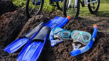 A pair of blue snorkeling fins and a snorkel on a rock with bicycles in the background.
