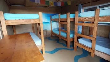 Ein kleines Ferienhäuschen mit Etagenbetten, einem Holztisch und einem Deckenventilator.