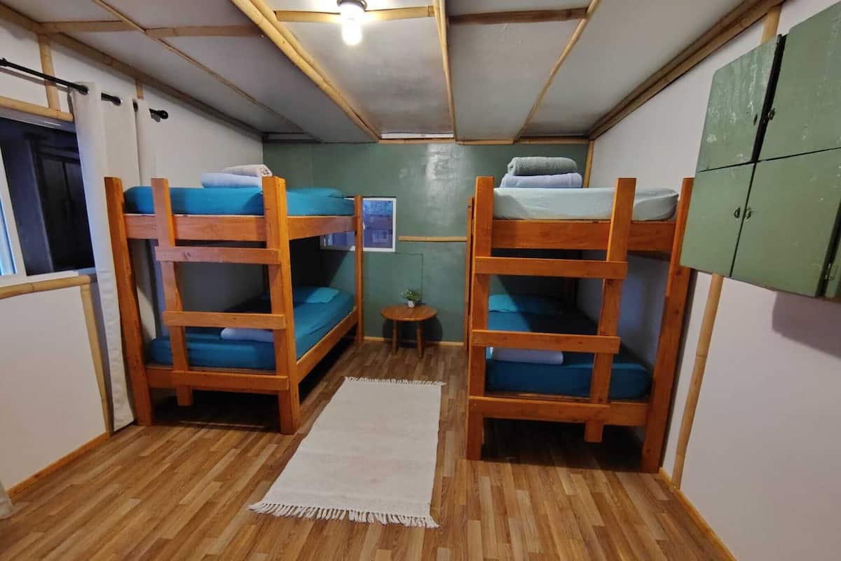 A room with bunk beds, a small table, and a green cabinet.