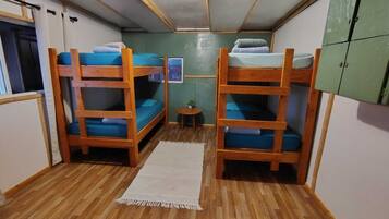 Una habitación con literas, una mesita pequeña y un armario verde.