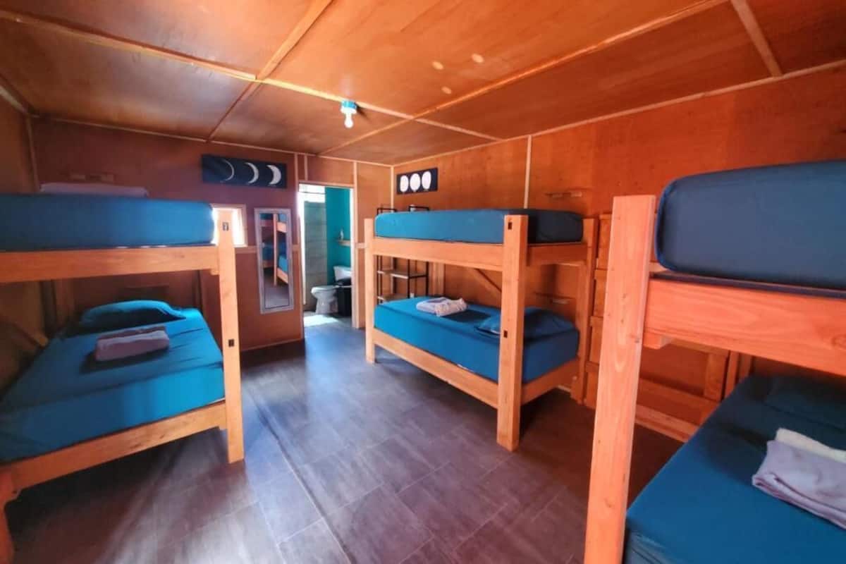 A cabin with bunk beds, wooden walls, and a tiled floor.