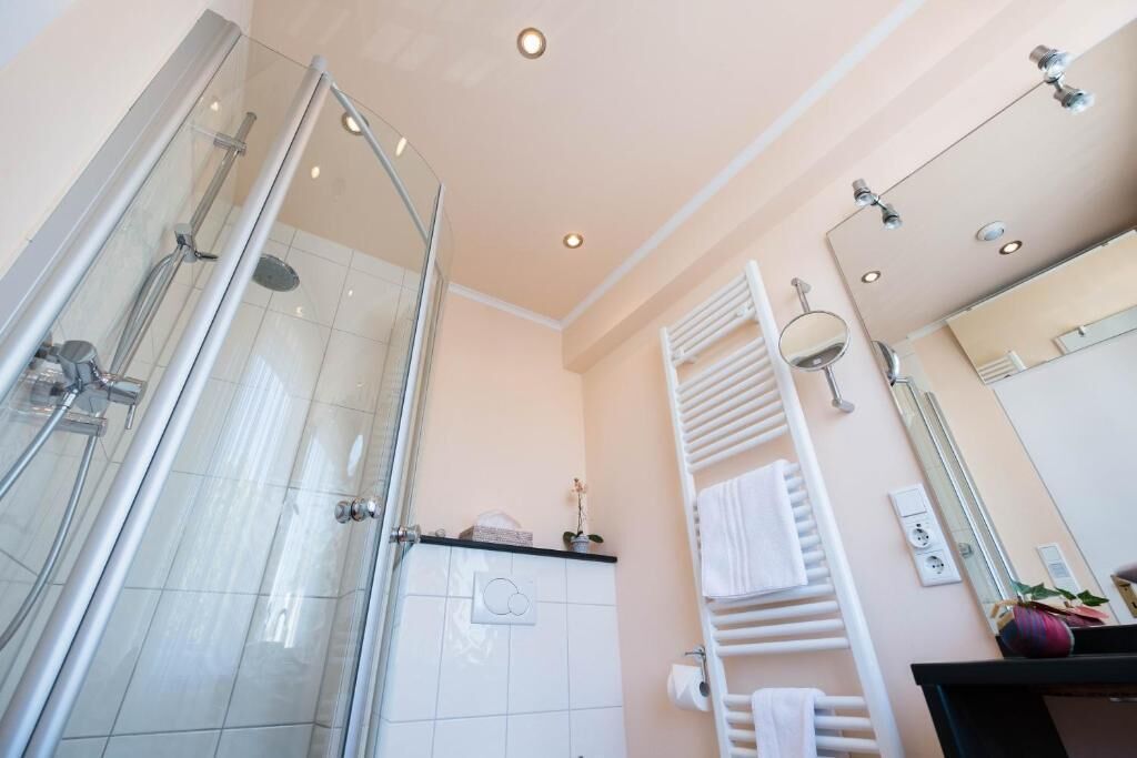 A modern bathroom with a glass-enclosed shower, a white towel rack, and a mirror above the sink.