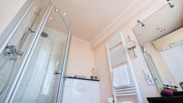 A modern bathroom with a glass-enclosed shower, a white towel rack, and a mirror above the sink.