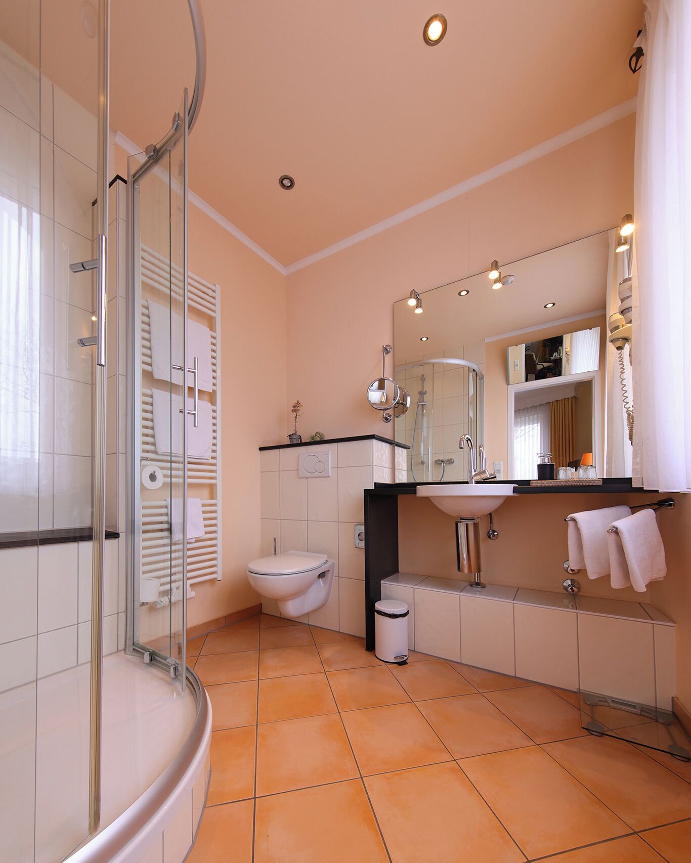 Une salle de bain moderne avec une douche à parois de verre, des toilettes, un lavabo et un grand miroir.