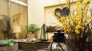 A cozy patio area with potted plants, a lantern, and a decorative vase. - Hotel zur Mühle (Paderborn)