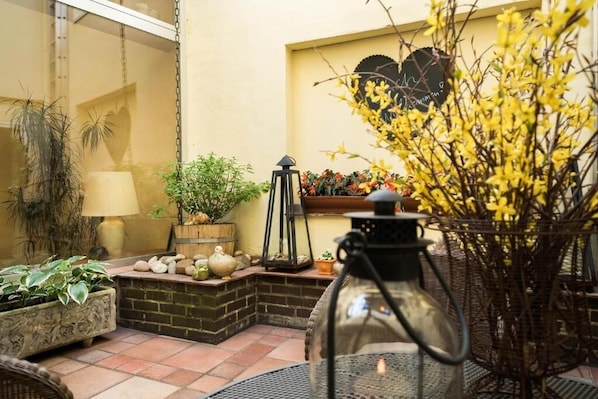 Een gezellig terras met potplanten, een lantaarn en een decoratieve vaas.