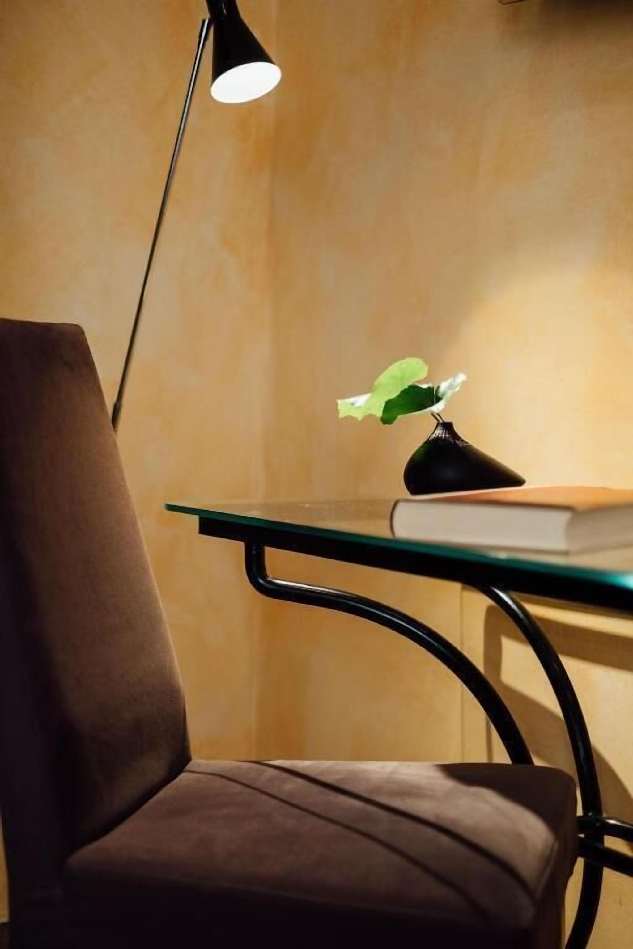 Una silla, una mesa, una lámpara y una planta.