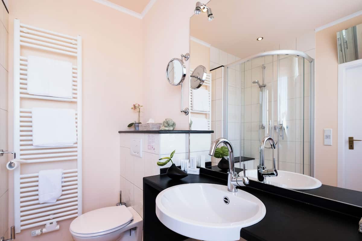A modern bathroom with a white sink, a large mirror, and a glass shower enclosure.