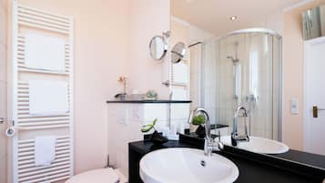 Ein modernes Badezimmer mit einem weißen Waschbecken, einem großen Spiegel und einer Duschkabine aus Glas.