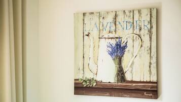 Una obra de arte colgada en la pared con la palabra "LAVENDER" y un jarrón con flores de lavanda.