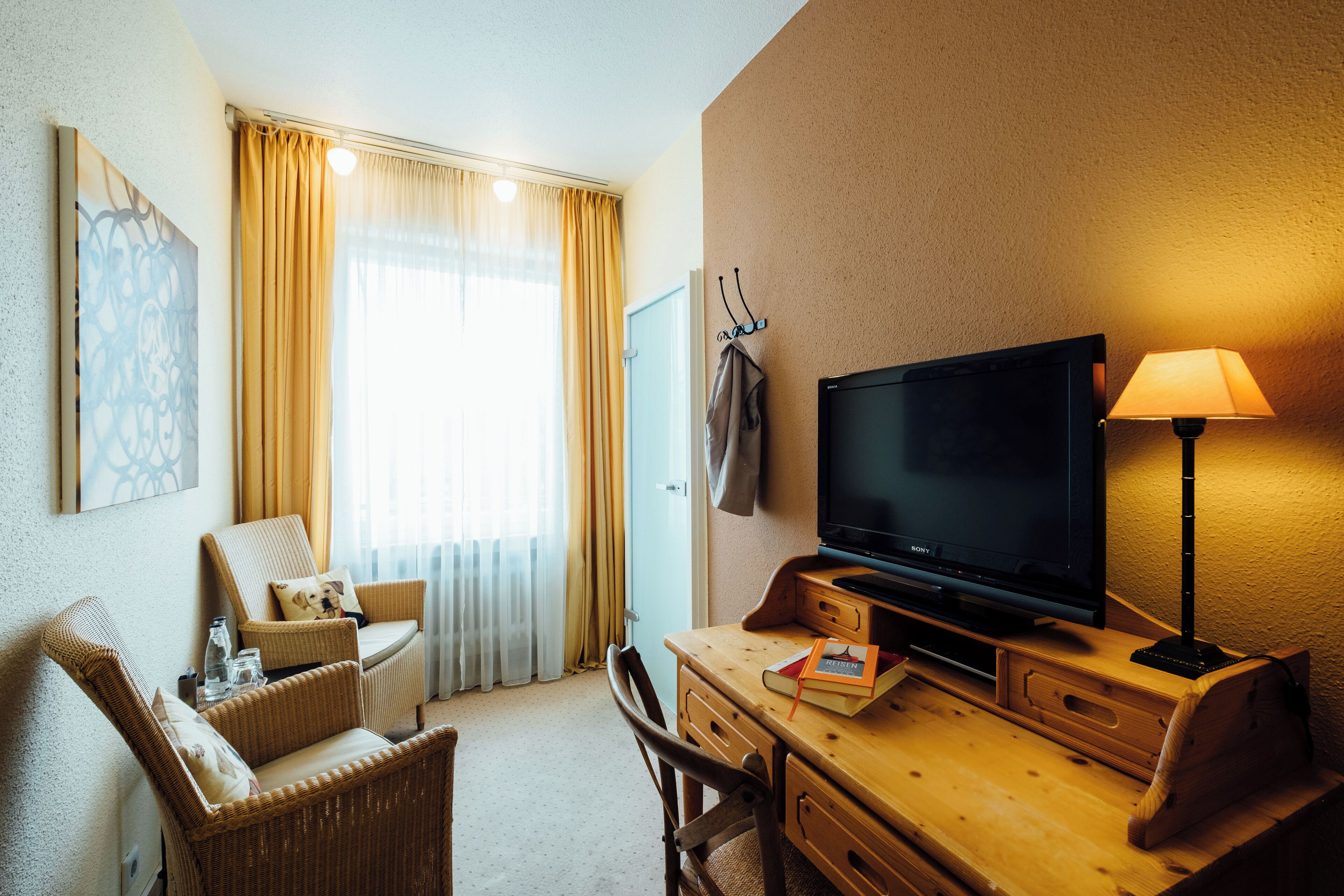 Habitación de hotel con televisión, escritorio, silla y lámpara.