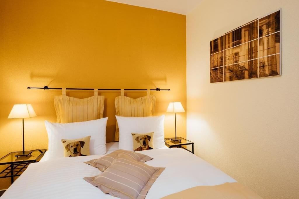 A hotel room with a bed, two bedside tables, lamps, and a framed picture on the wall.