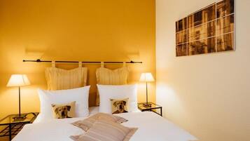 A hotel room with a bed, two bedside tables, lamps, and a framed picture on the wall.