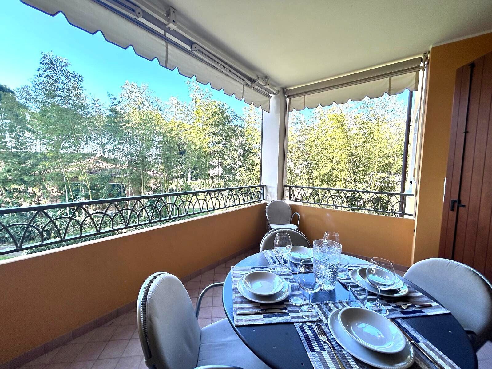 Un balcón con una mesa para dos, con vistas a un paisaje pintoresco de árboles y colinas.