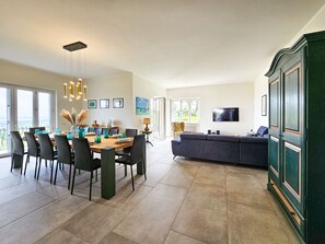 A spacious living area with a dining table, chairs, a sofa, and a television. - Villa Venti_Exclusive Property with Pool & View (Puegnago sul Garda)