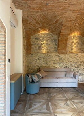 A cozy room with a stone wall, a wooden ceiling, and a patterned floor. - Dimora del Torchio – Panoramic Pool and Jacuzzi (Soiano del Lago)