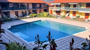 A pool area with a checkered floor, surrounded by buildings with balconies and a red-tiled roof. - Casa Magenta_Private Garden & Swimming Pool in the Village (Moniga del Garda)