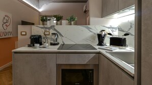 Una cocina moderna con encimeras de mármol, horno empotrado y cafetera.