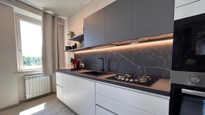 Een moderne keuken met een gasfornuis, een inbouwoven en een raam met gordijnen.