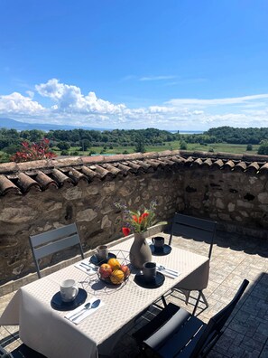 An outdoor dining area with a table set for two, a vase with flowers, and a view of the countryside. - The cottage at Borgo Alba_Charm in a historic courtyard (Polpenazze del Garda)