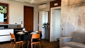A modern living room with a grey sofa and a dining area with a table and chairs. - Casa Pratello_Design and relax with a view of the lake (Padenghe sul Garda)