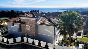 A modern house with a tiled roof, stone walls, and a view of the sea. - Casa Pratello_Design and relax with a view of the lake (Padenghe sul Garda)