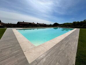 Una piscina rectangular con un borde de baldosas alrededor.