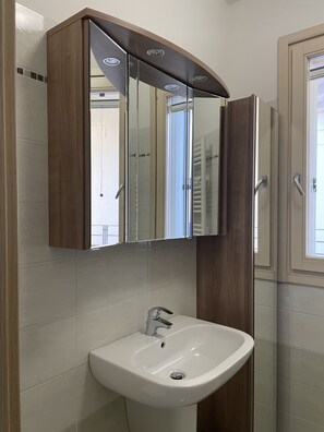 A bathroom with a white sink, a mirror above it, and wooden cabinetry.