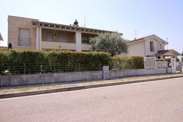 A residential building with a balcony, a stone facade, and a small tower-like structure on the roof.