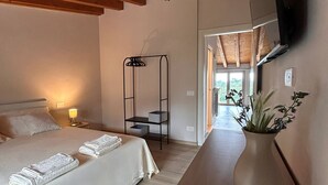 A hotel room with a bed, bedside table, and a TV mounted on the wall. - Borgo Alba Lake View Loft_Design in the Historic Village (Polpenazze del Garda)