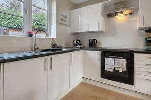 A modern kitchen with white cabinets, a black oven, and a window with a view of greenery.