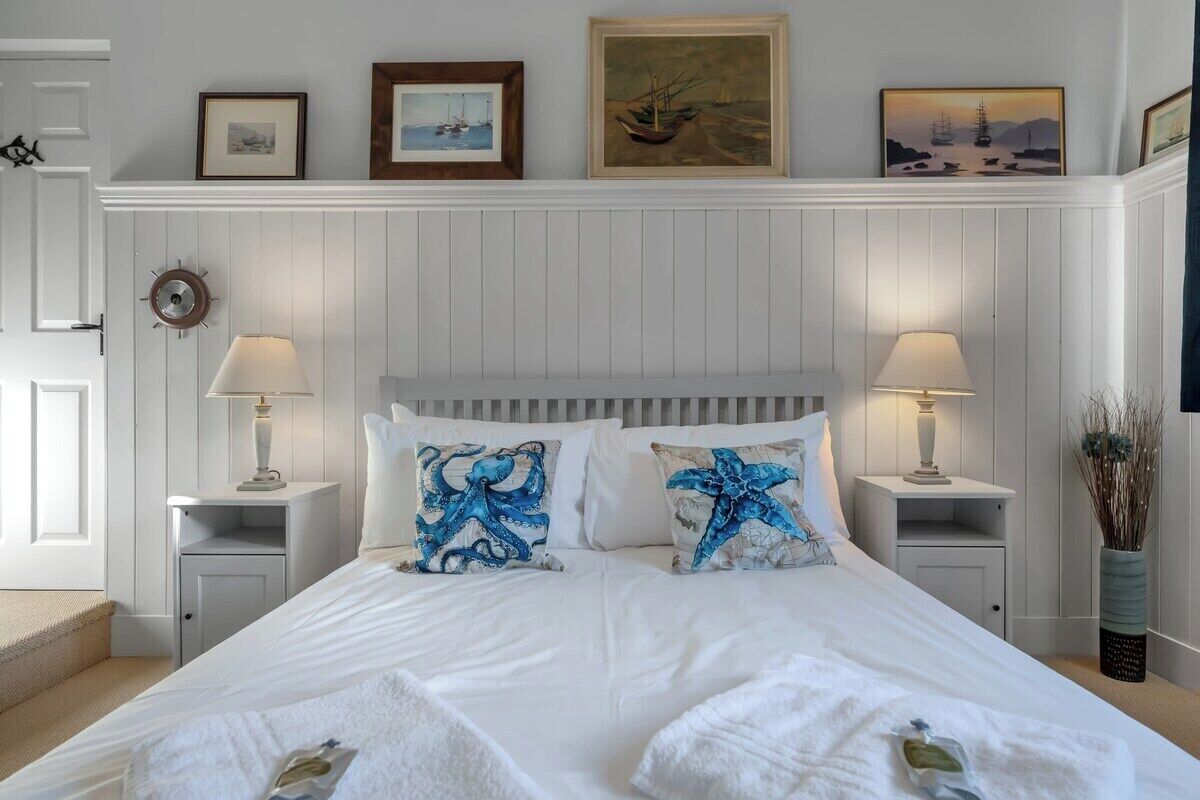 A neatly arranged bedroom with a bed, two bedside tables, and a wall-mounted clock.