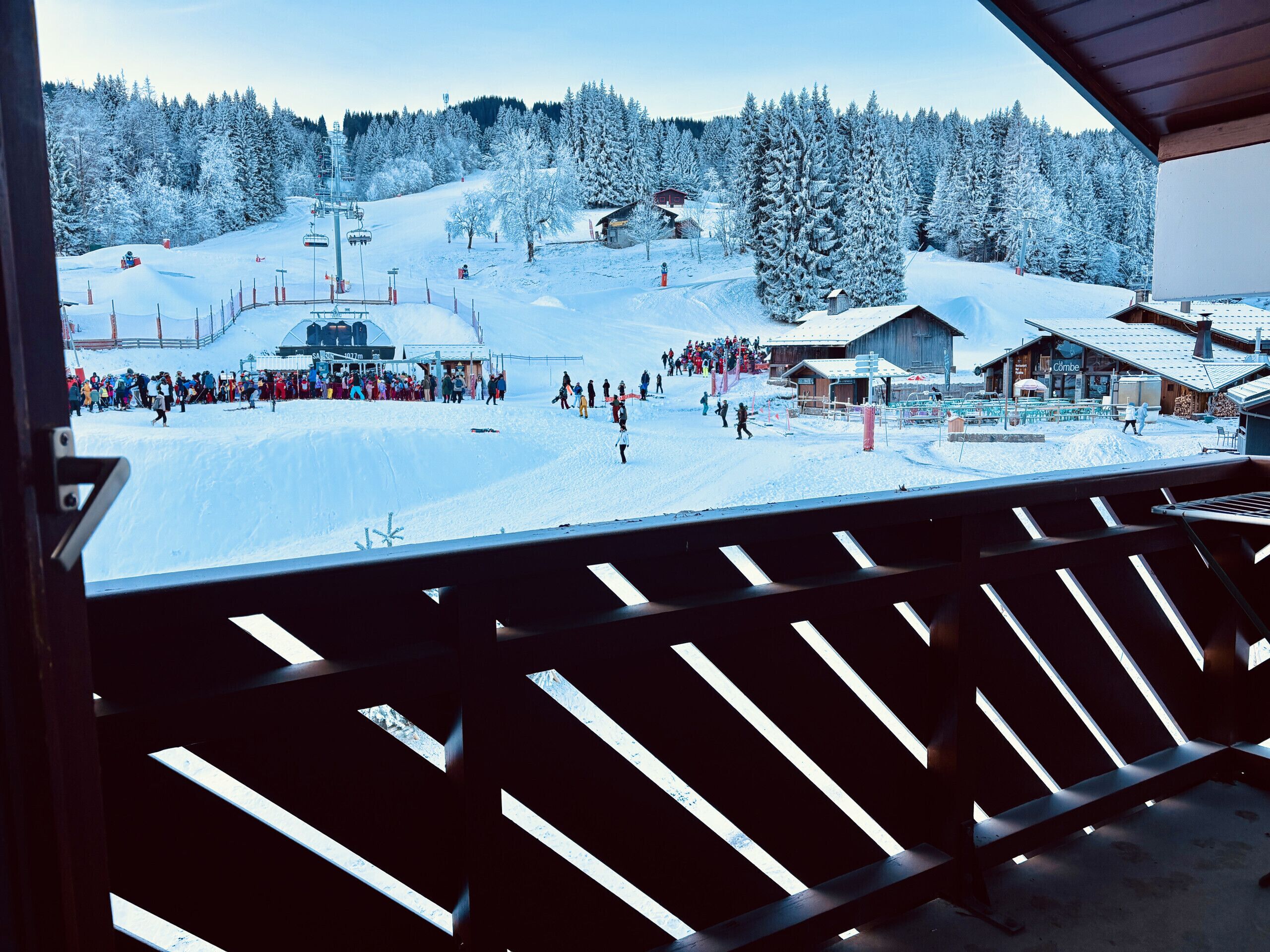 Ein verschneites Skigebiet mit Seilbahn, vielen Skifahrern und einem Gebäude mit dem Schriftzug 