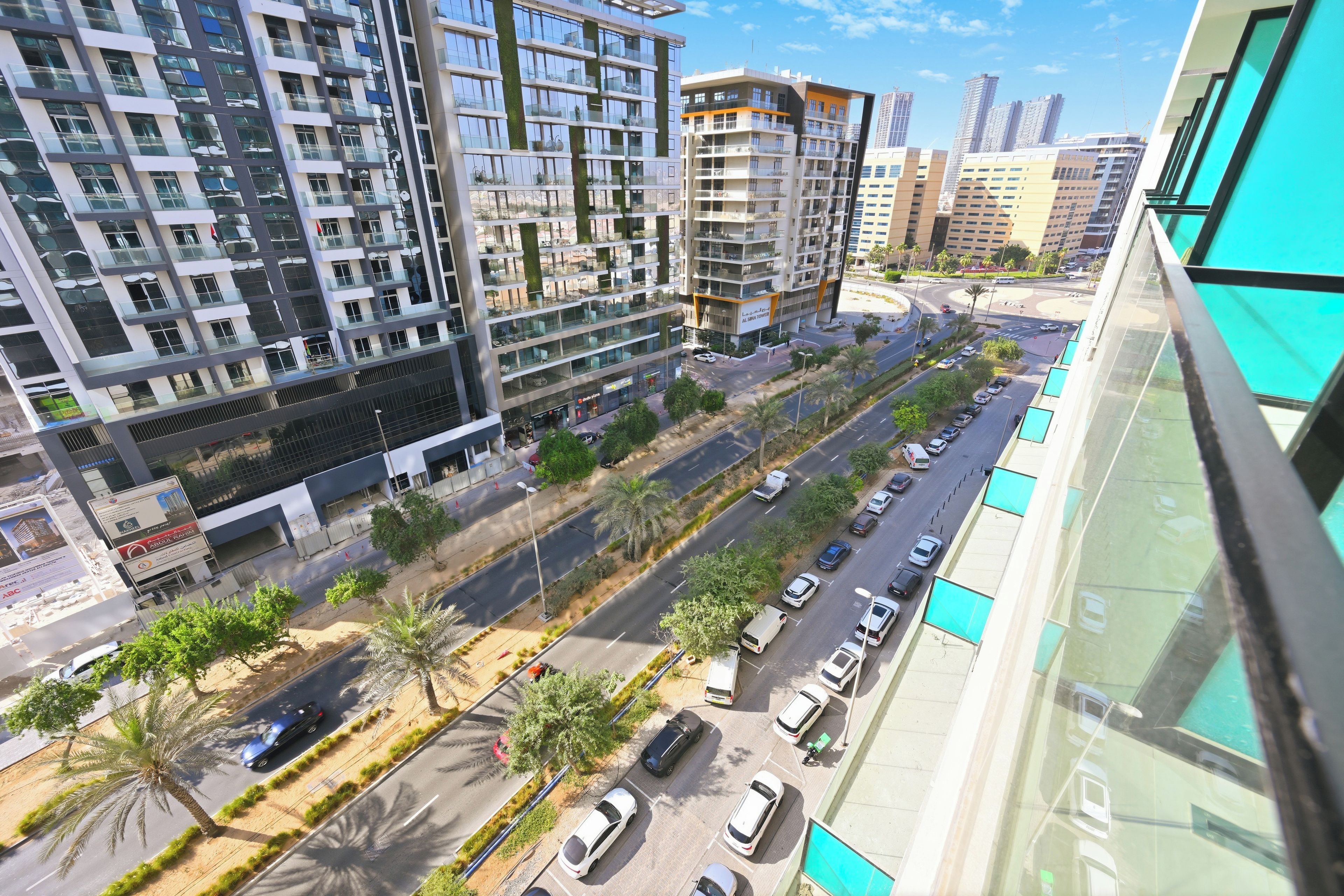 A modern high-rise building with multiple balconies and a street view below.