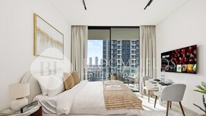 Ein modernes Hotelzimmer mit einem großen Bett, einem Schreibtisch, einem Sessel und einem Fernseher an der Wand.