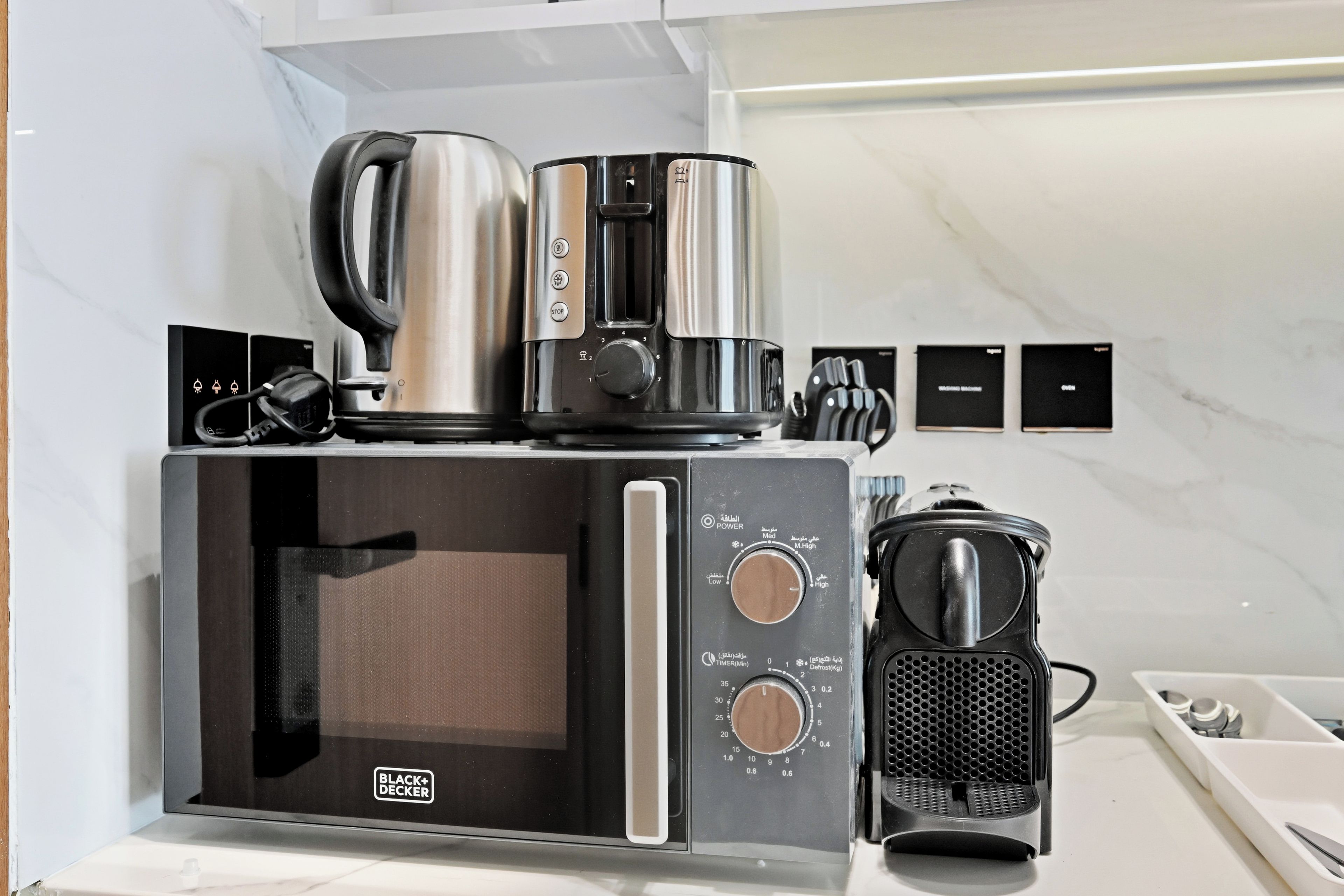Une cuisine compacte équipée d’un four à micro-ondes, d’une machine à café et d’une bouilloire.
