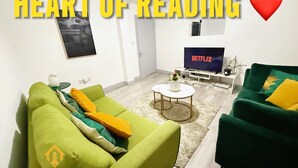Ein Wohnzimmer mit grünen Sofas, einem weißen Couchtisch und einem Fernseher für Netflix.
