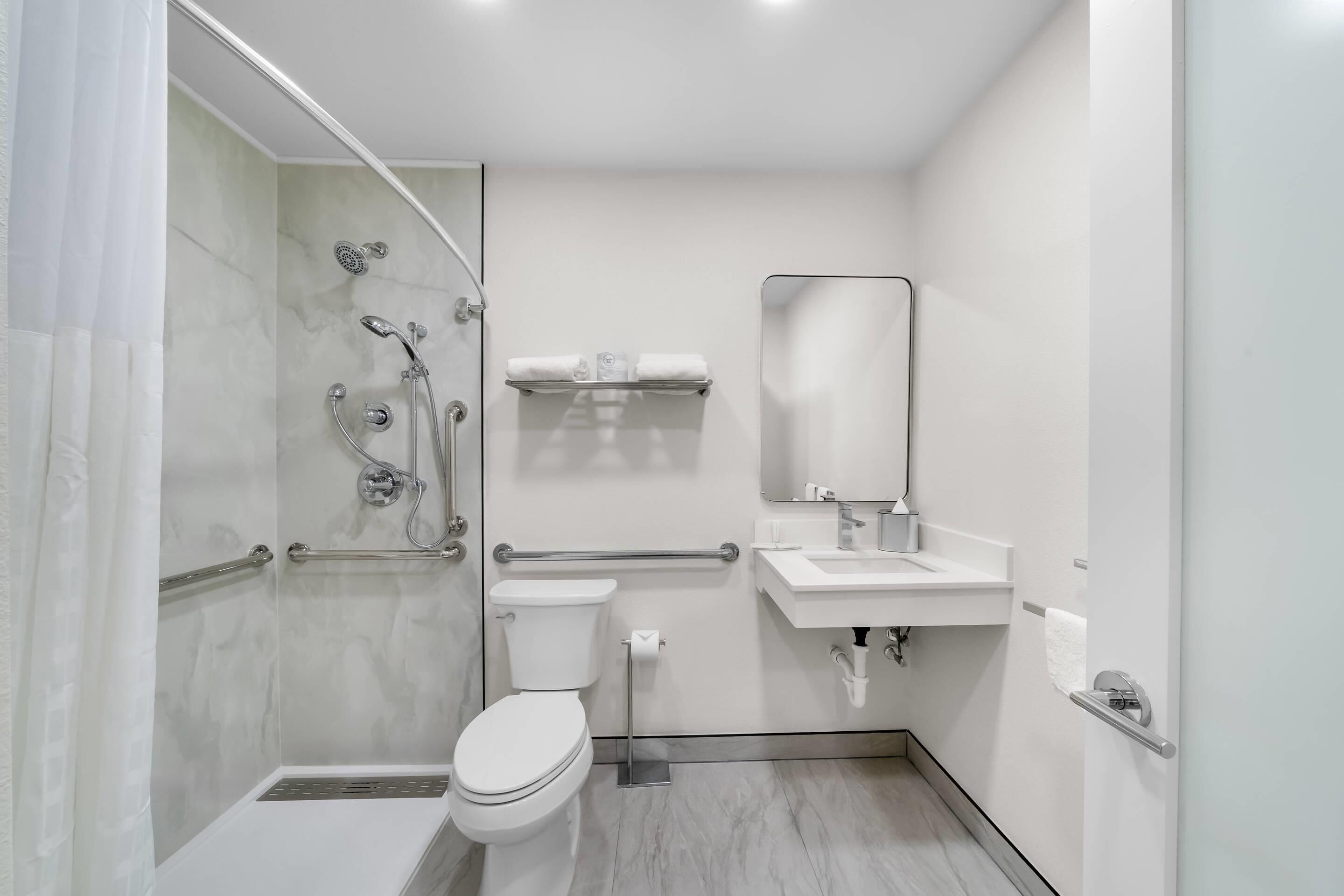 Une salle de bain moderne équipée d’une douche, de toilettes, d’un lavabo et d’un miroir.