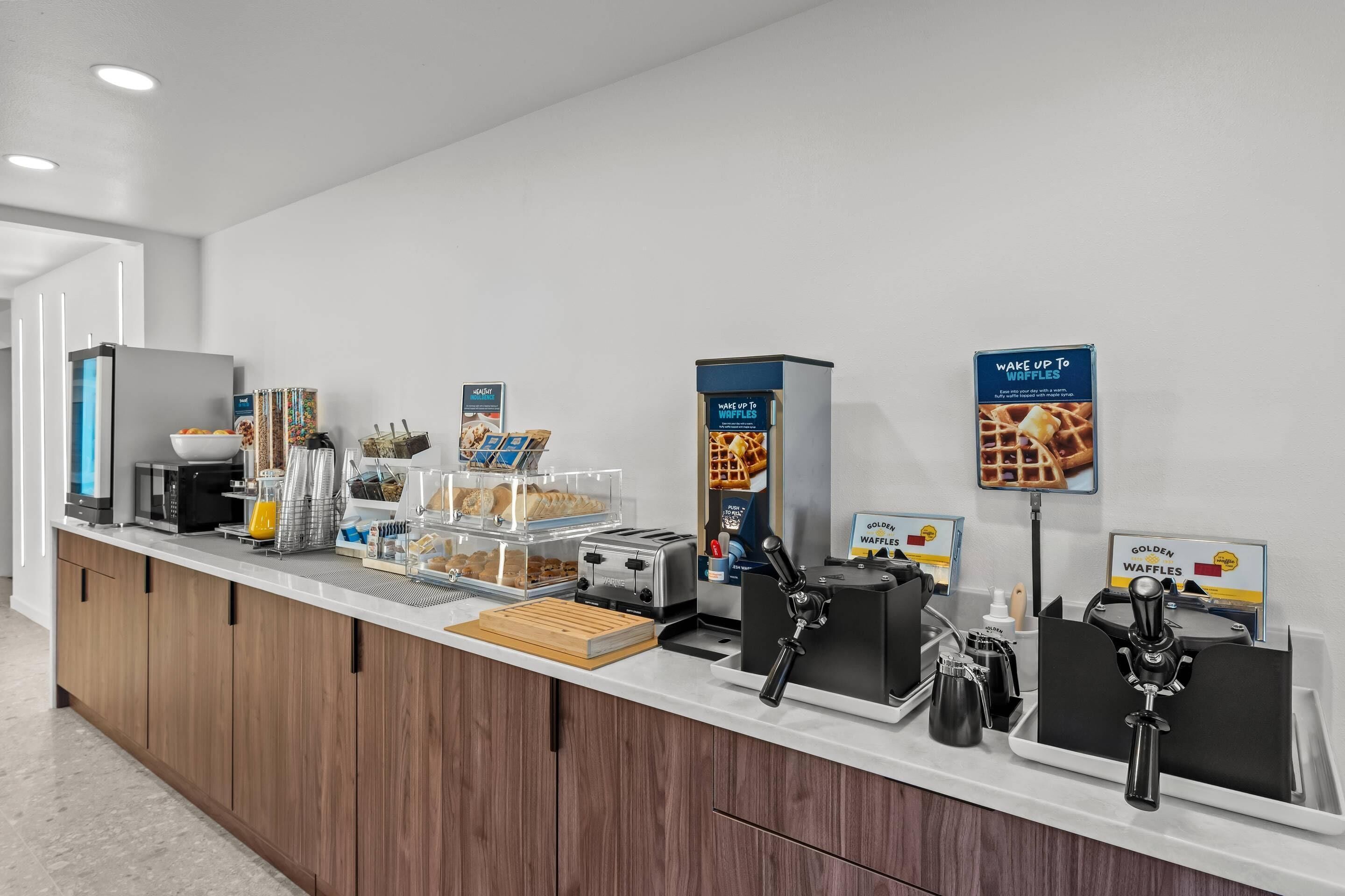 Ein Frühstücksbuffet mit Waffeleisen, einer Kaffeemaschine und einem Toaster.