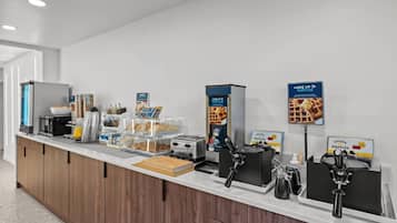 Ein Frühstücksbuffet mit Waffeleisen, einer Kaffeemaschine und einem Toaster.