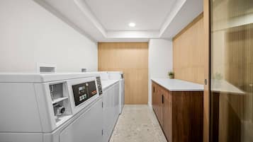 A laundry room with a washing machine, a dryer, and a wooden cabinet.