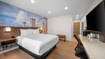 Habitación de hotel con cama, escritorio, televisor y un mural de noria.