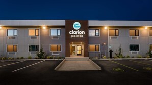 Un hôtel doté d’une façade moderne, d’un logo bien visible et d’un parking avec des places délimitées.