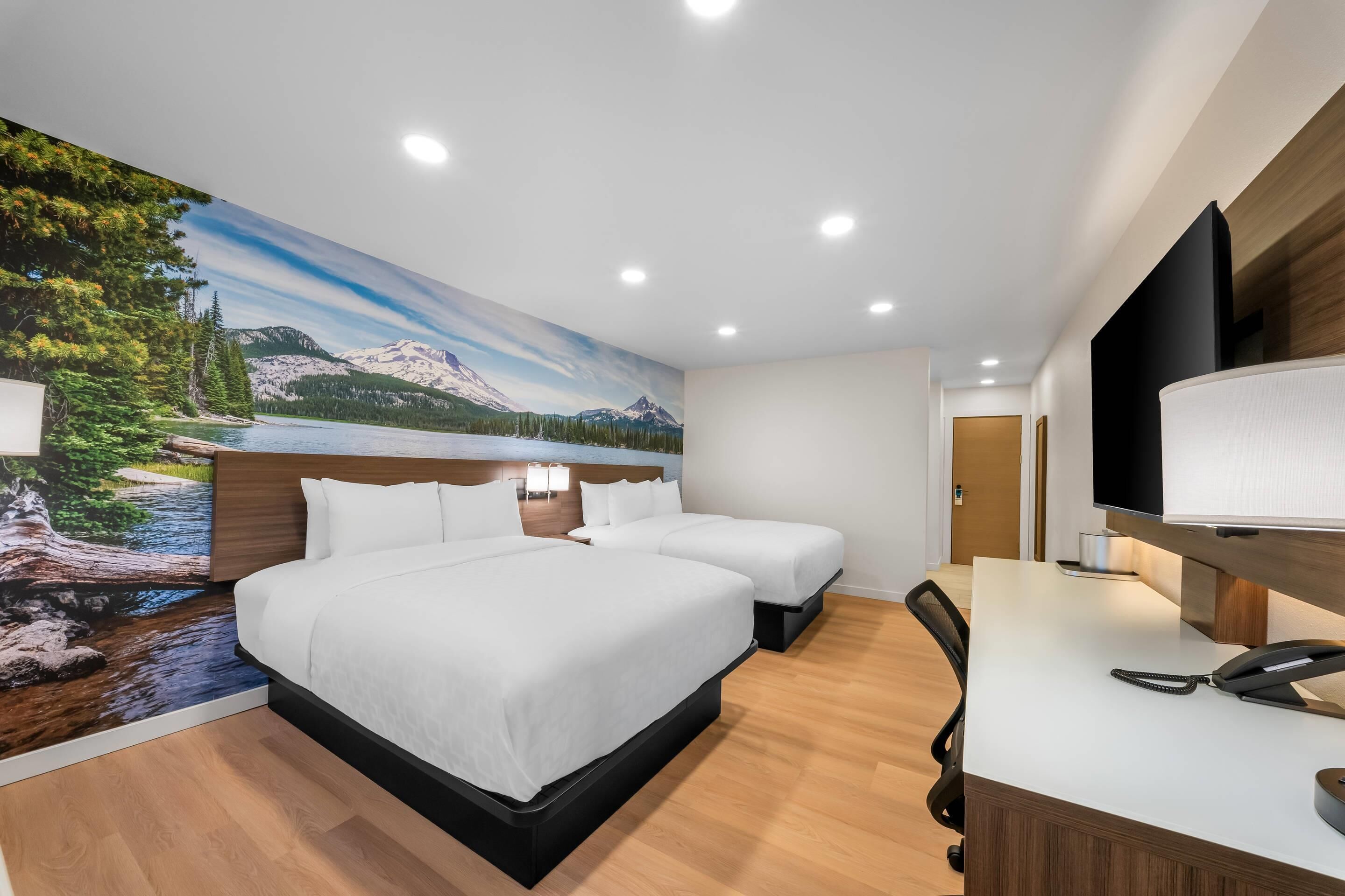 A hotel room with a large bed, two bedside tables, a desk with a phone, and a TV.