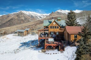 A wooden cabin with a balcony and a hot tub, surrounded by snow-covered mountains. - Mountain Retreat w/ Fire Table, Hot Tub & Library Loft (Telluride)