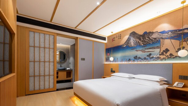 A hotel room with a bed, a bedside table with a phone, a wall-mounted light, and a traditional Japanese sliding door. - Days Inn by Wyndham Changsha Kaifu (Changsha)