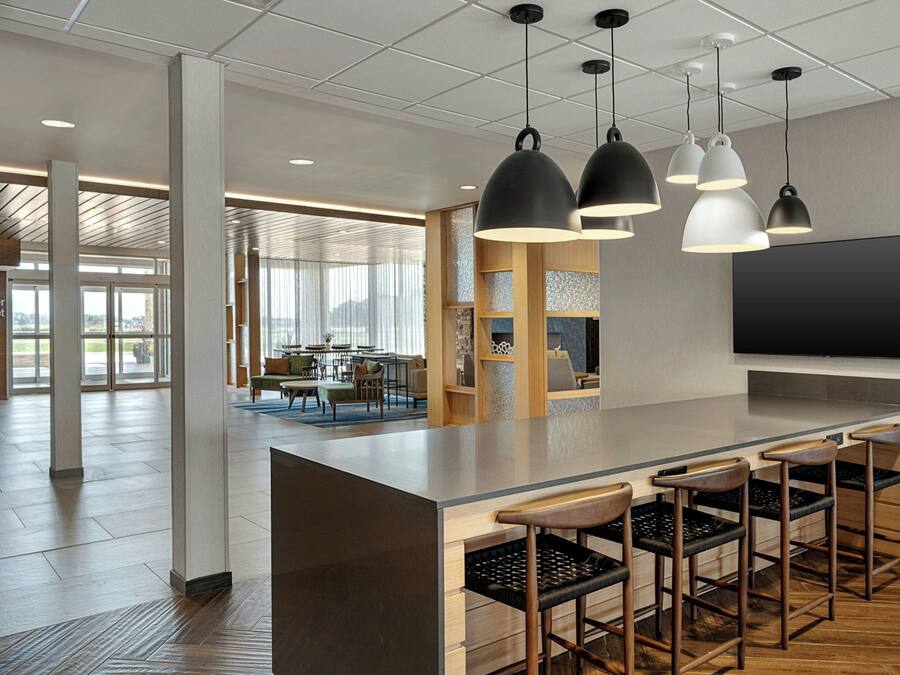 A modern interior with a bar area, seating, and a large flat-screen TV.