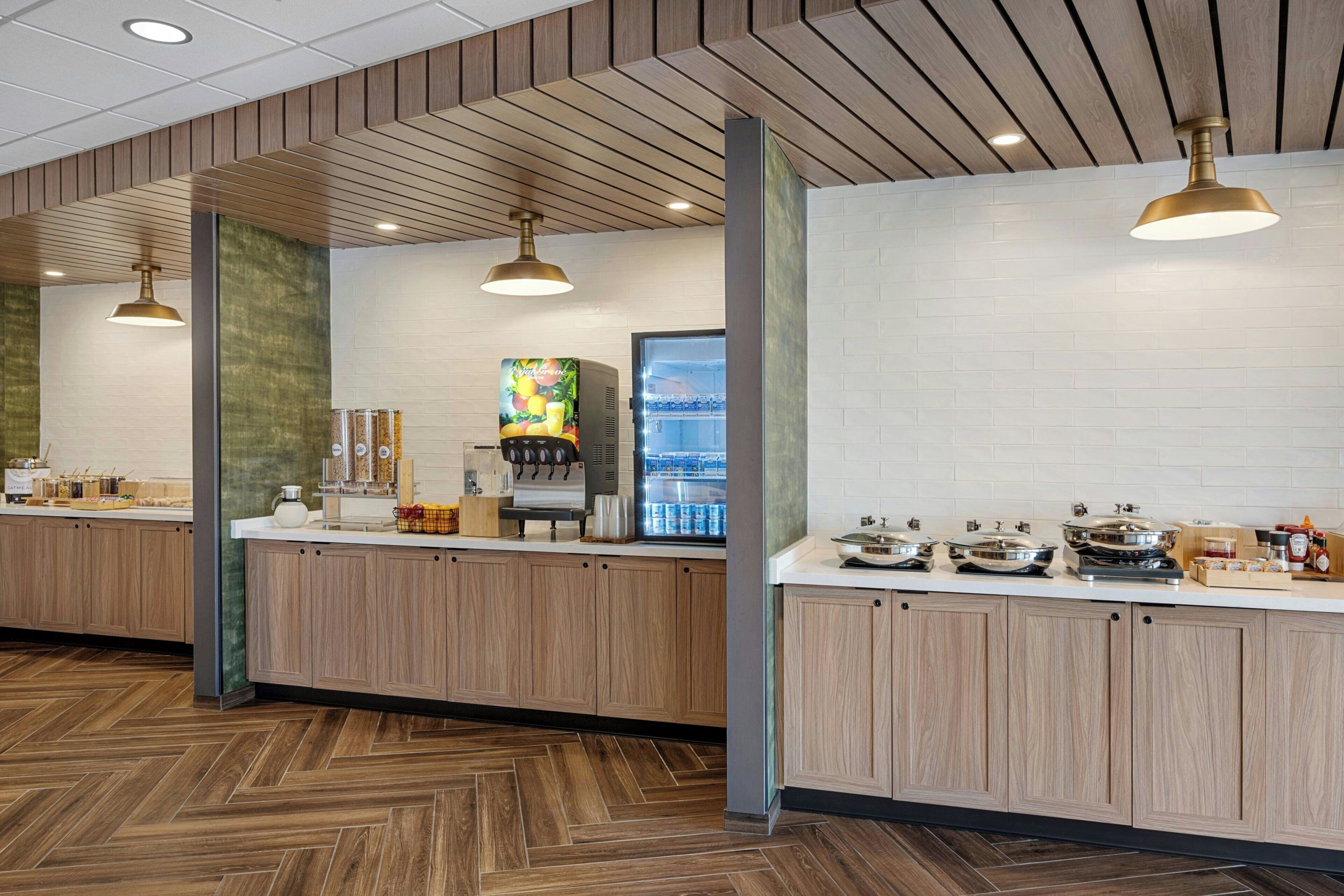 A modern kitchen area with wooden cabinets, a coffee machine, and a refrigerator.