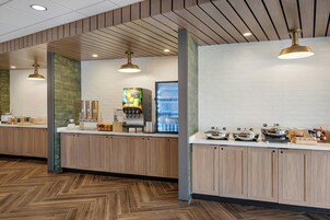 Un área de cocina moderna con armarios de madera, una cafetera y un refrigerador.