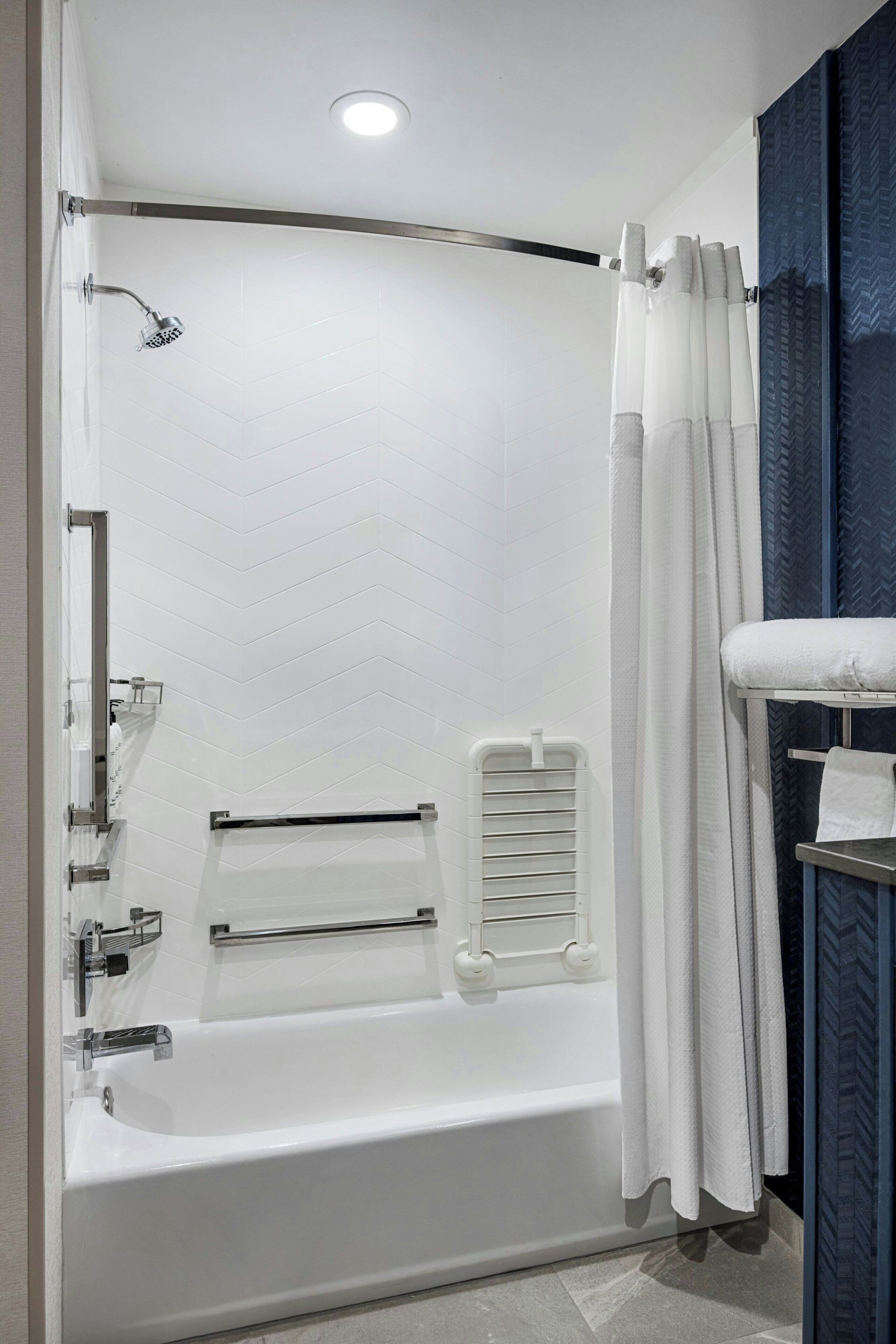A modern bathroom with a bathtub, shower, and a towel rack.